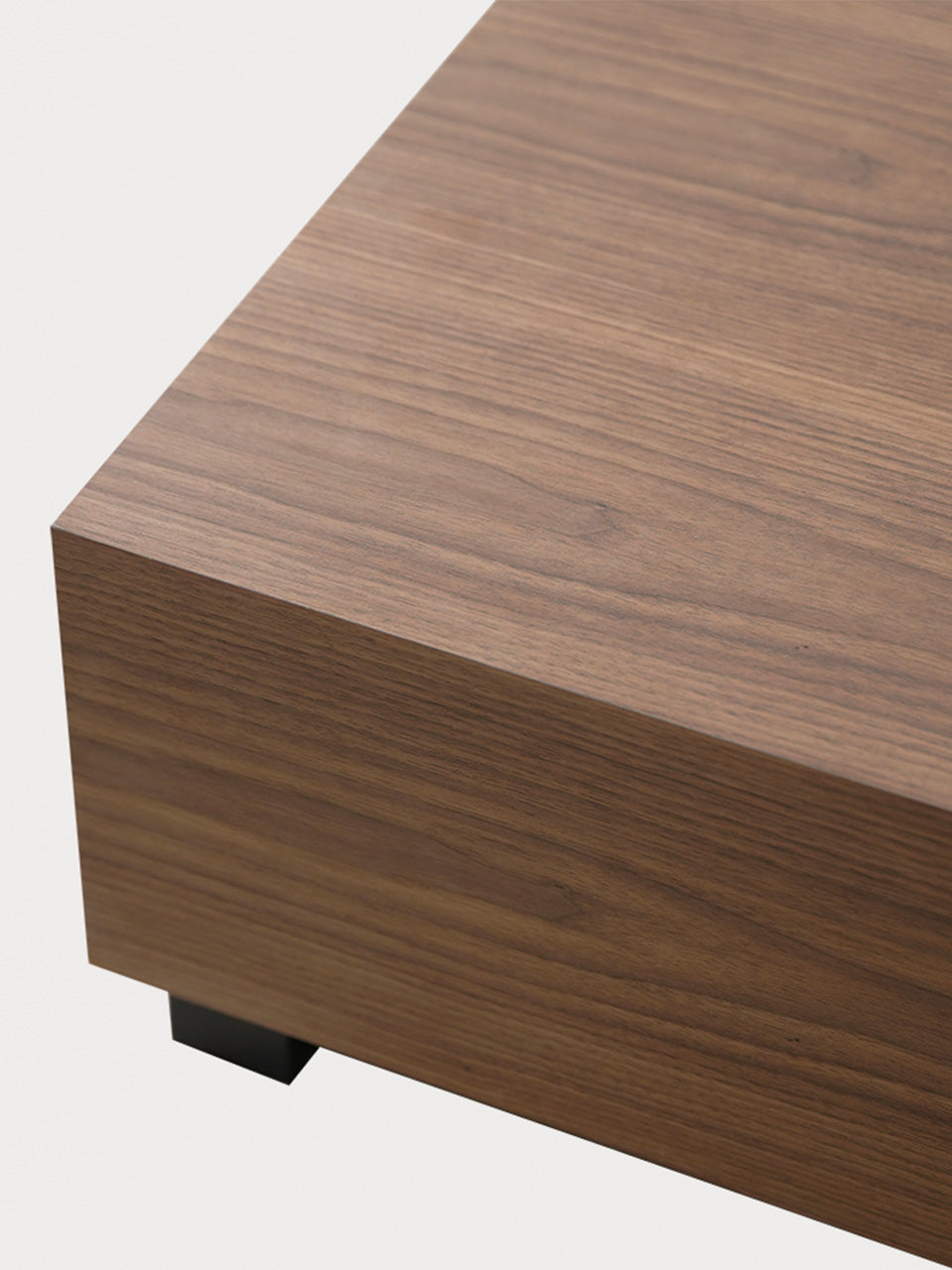 Detalle de tablero de mesa de centro cuadrada en madera de nogal y patas negras.