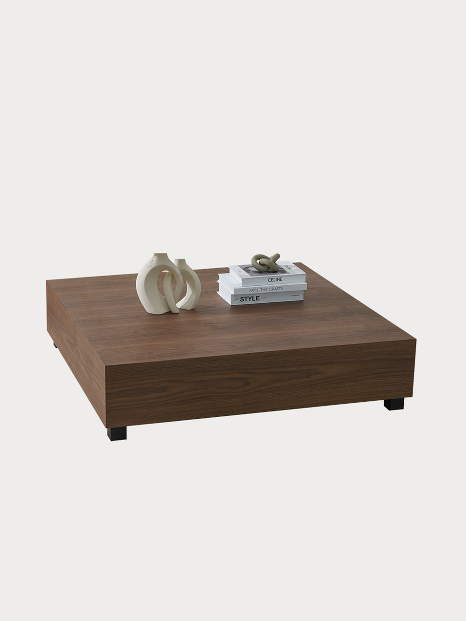 Mesa de centro cuadrada en madera de nogal con decoración sobre ella en vista frontal lateral.