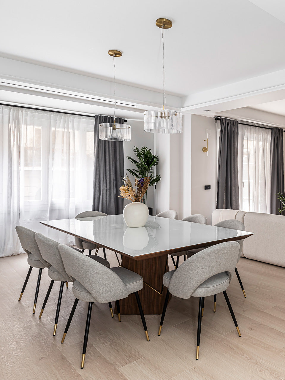 Mesa de comedor rectangular en madera y detalles metálicos de latón en comedor luminoso.