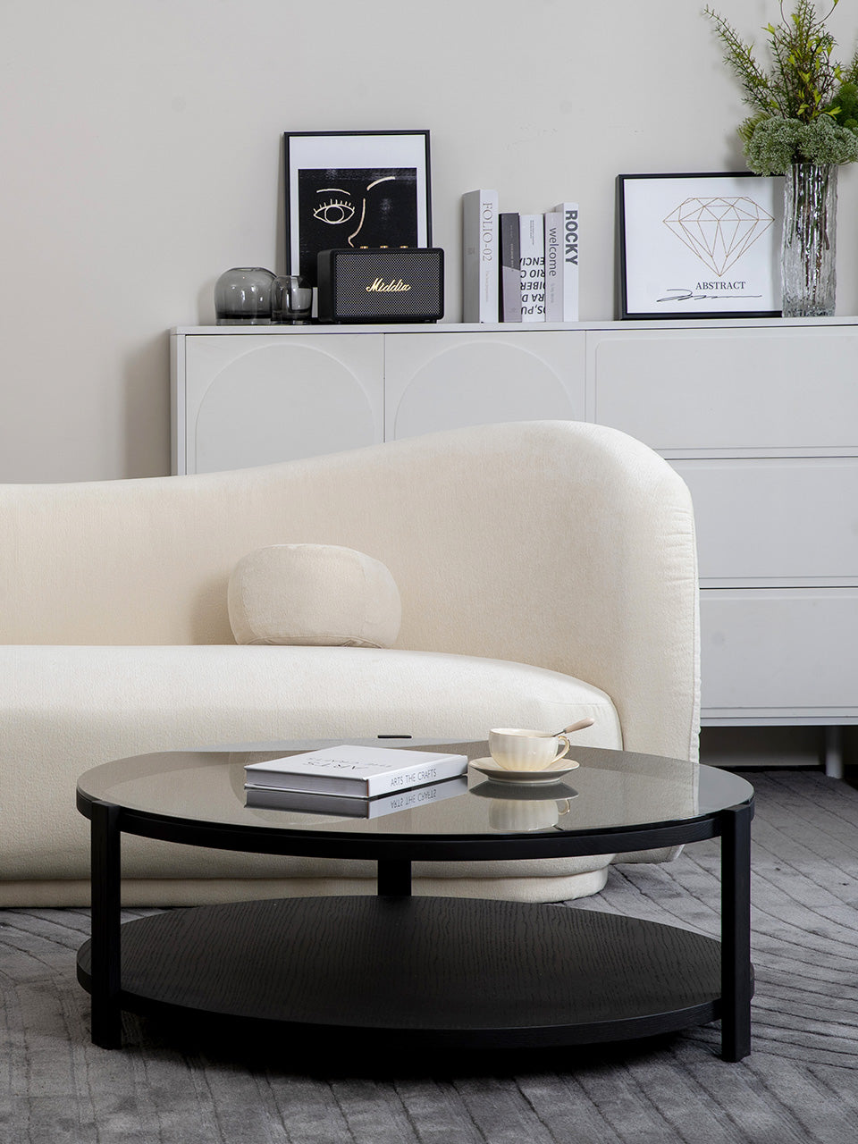 Mesa de centro redonda con un tablero de 90 cm de diámetros en vidrio templado y estructura de metal y madera en salón.