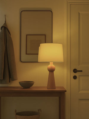 Lámpara de mesa con base de madera y pantalla tela, disponible en 2 colores.