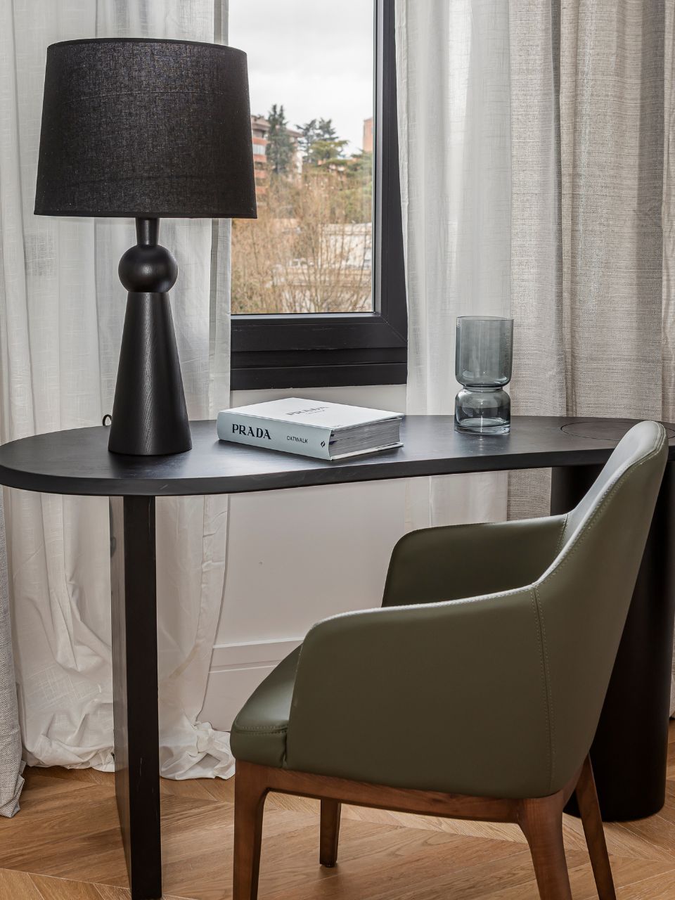 Mesa de escritorio de madera chapada negra en vista lateral en ambiente.