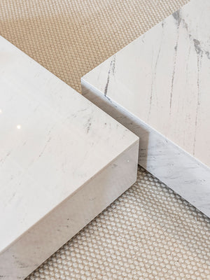 Detalle de tablero de mesa de centro cuadrada en mármol blanco con vetas grises.