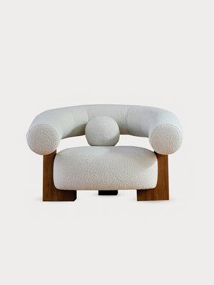 Sillón en tejido bouclé con puf en vista frontal.