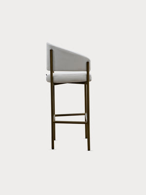 Taburete alto en tejido de tela de ante beige y patas metalizadas en vista lateral.